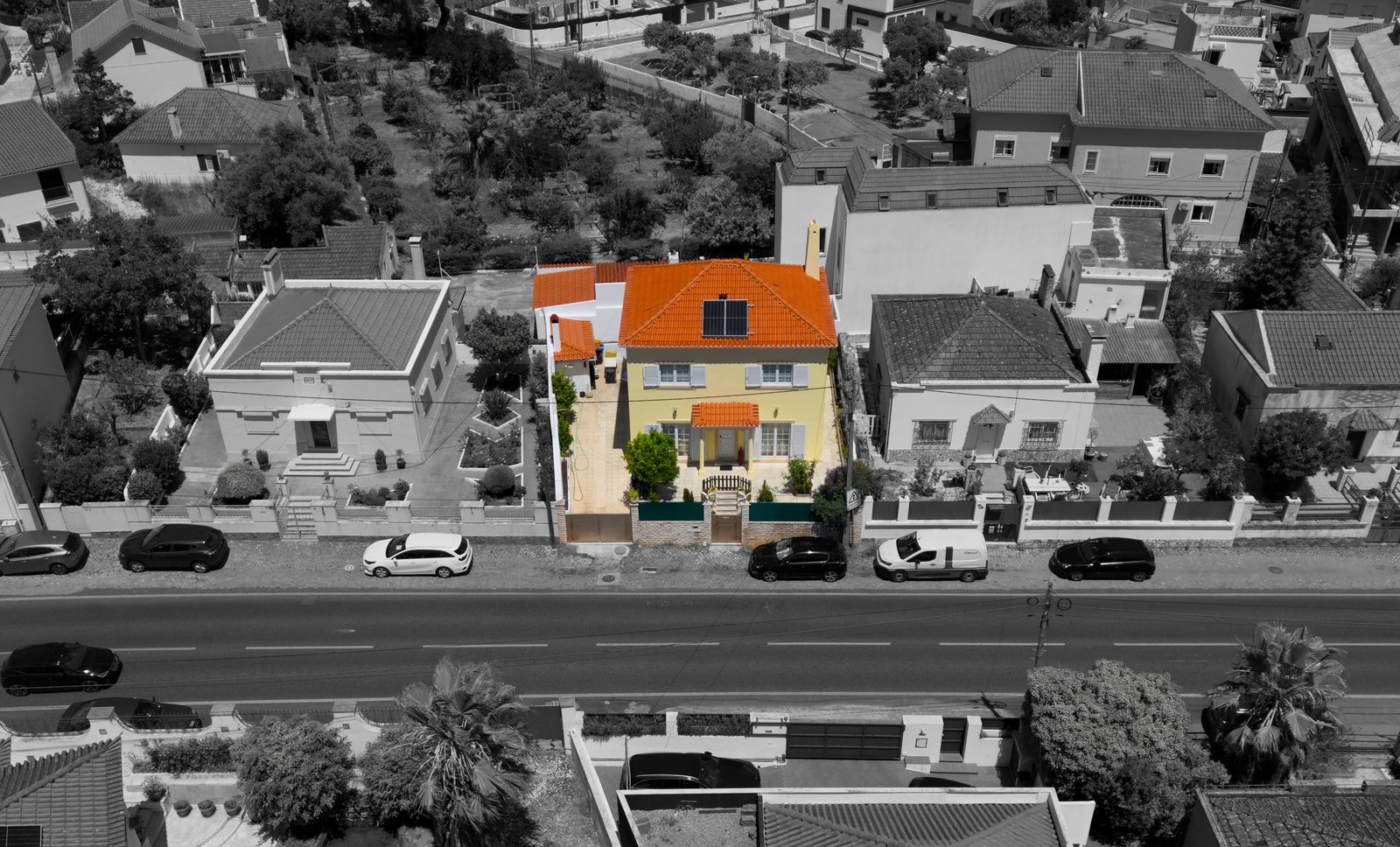 Fachada da moradia realçada a cor sobre a rua a preto e branco